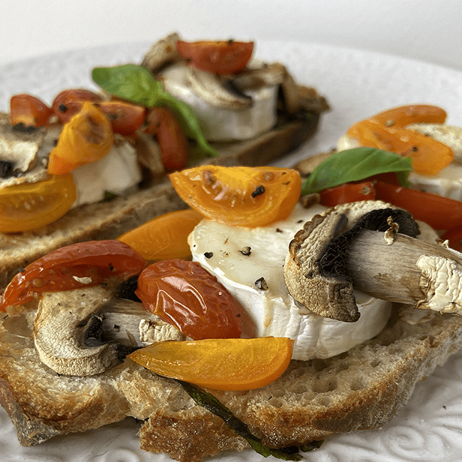 photographie de deux bruschetta tomate, chèvre et champignons