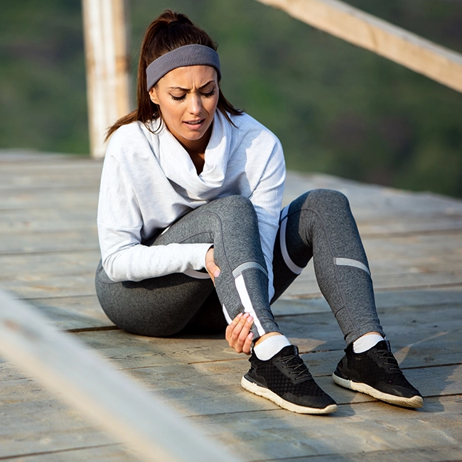 Femme qui se tient la jambe après une blessure