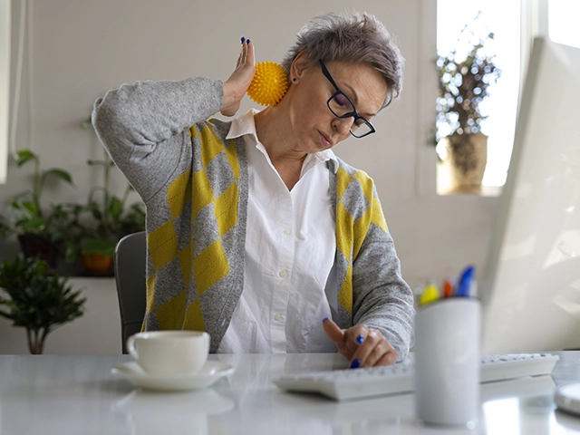 Femme qui se masse la nuque au travail