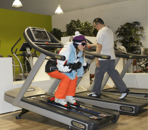 Ancienne photo vintage Elancia : femme en séance cardio sur tapis de course avec accessoires ski."